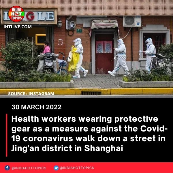Health workers wearing protective gear as a measure against the Covid-19 coronavirus walk down a street in Jing’an district in Shanghai