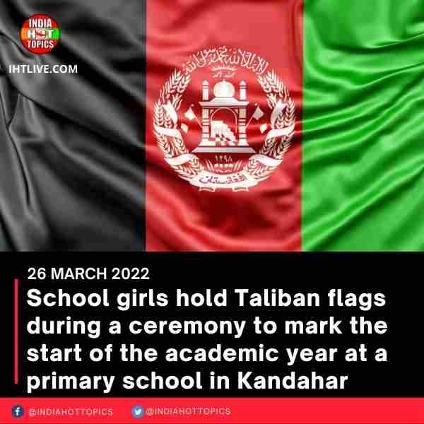School girls hold Taliban flags during a ceremony to mark the start of the academic year at a primary school in Kandahar